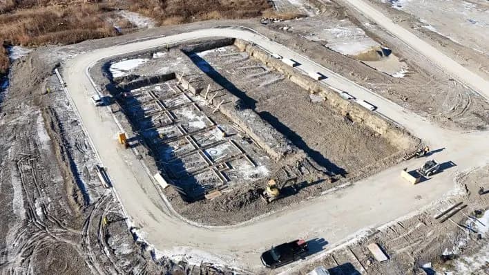 Aerial view of an excavated site in winter with concrete strip footings poured in rows.