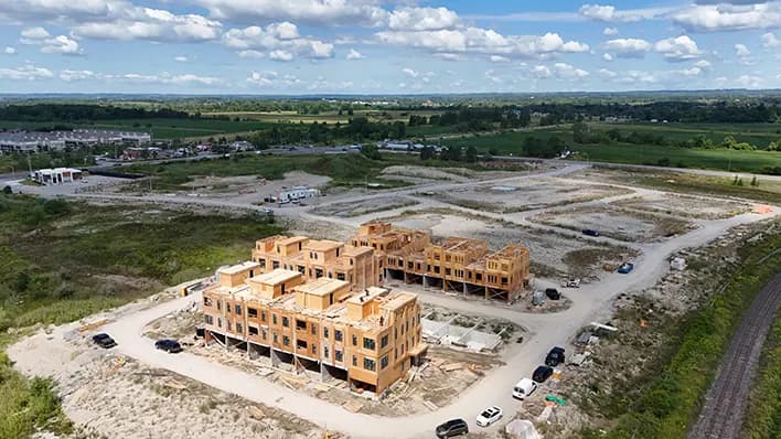 Aerial view of townhome blocks framed to full height in timber, beside a rail corridor.